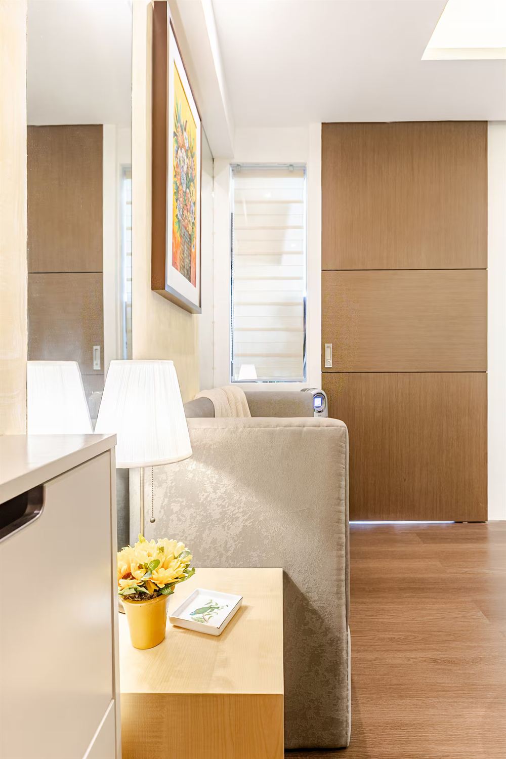 A corner of the living area — a soft sofa, a table lamp and a framed floral painting